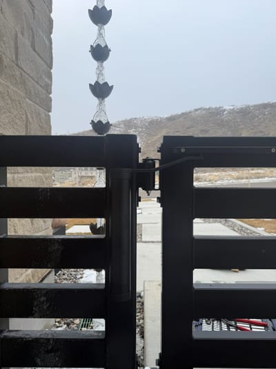 Gate hardware and closer detail on a black steel entrance gate.