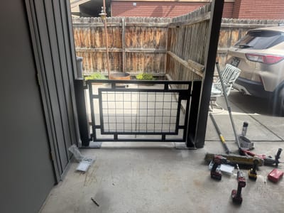 Black steel pedestrian gate with mesh infill panel.