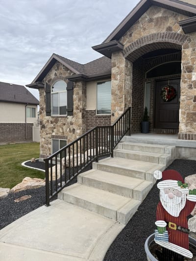 Dark bronze steel stairway railing on stone entry steps.