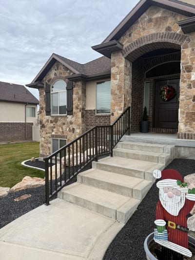 Dark bronze steel stairway railing on stone entry steps.